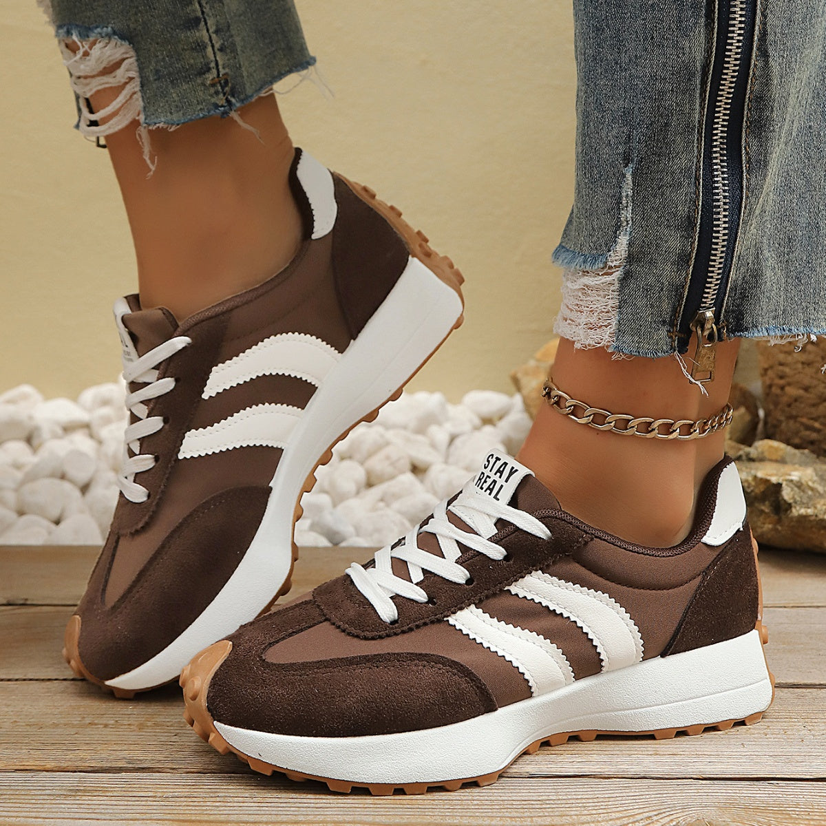 Brown lace-up sneakers with round toe, white stripes, and cushioned padded collar