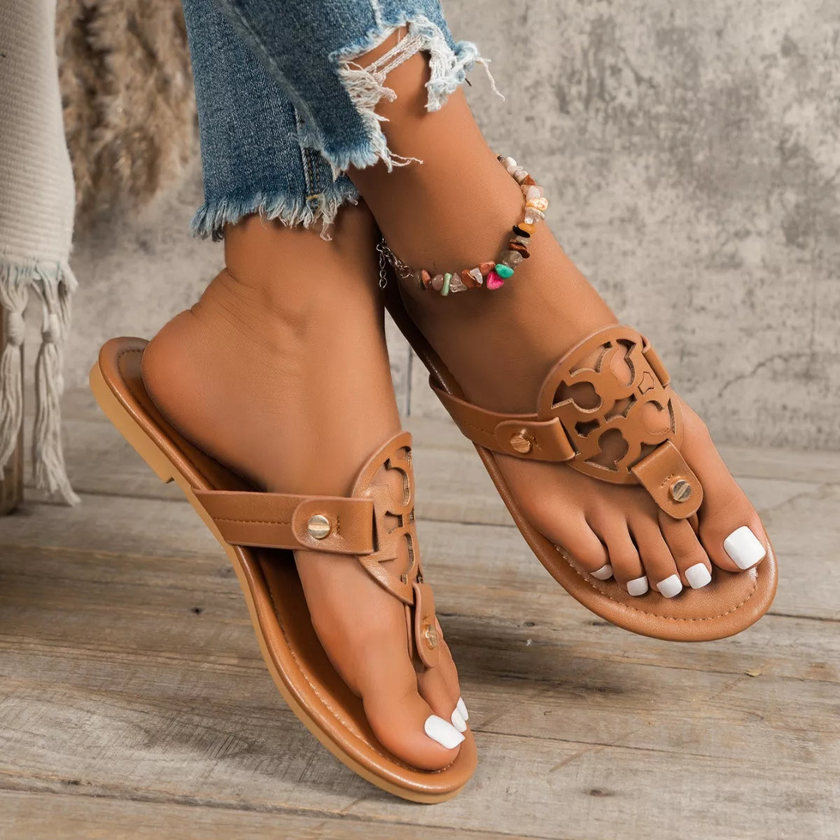 Tan brown flat thong sandals with cutout logo strap and metal buckle details