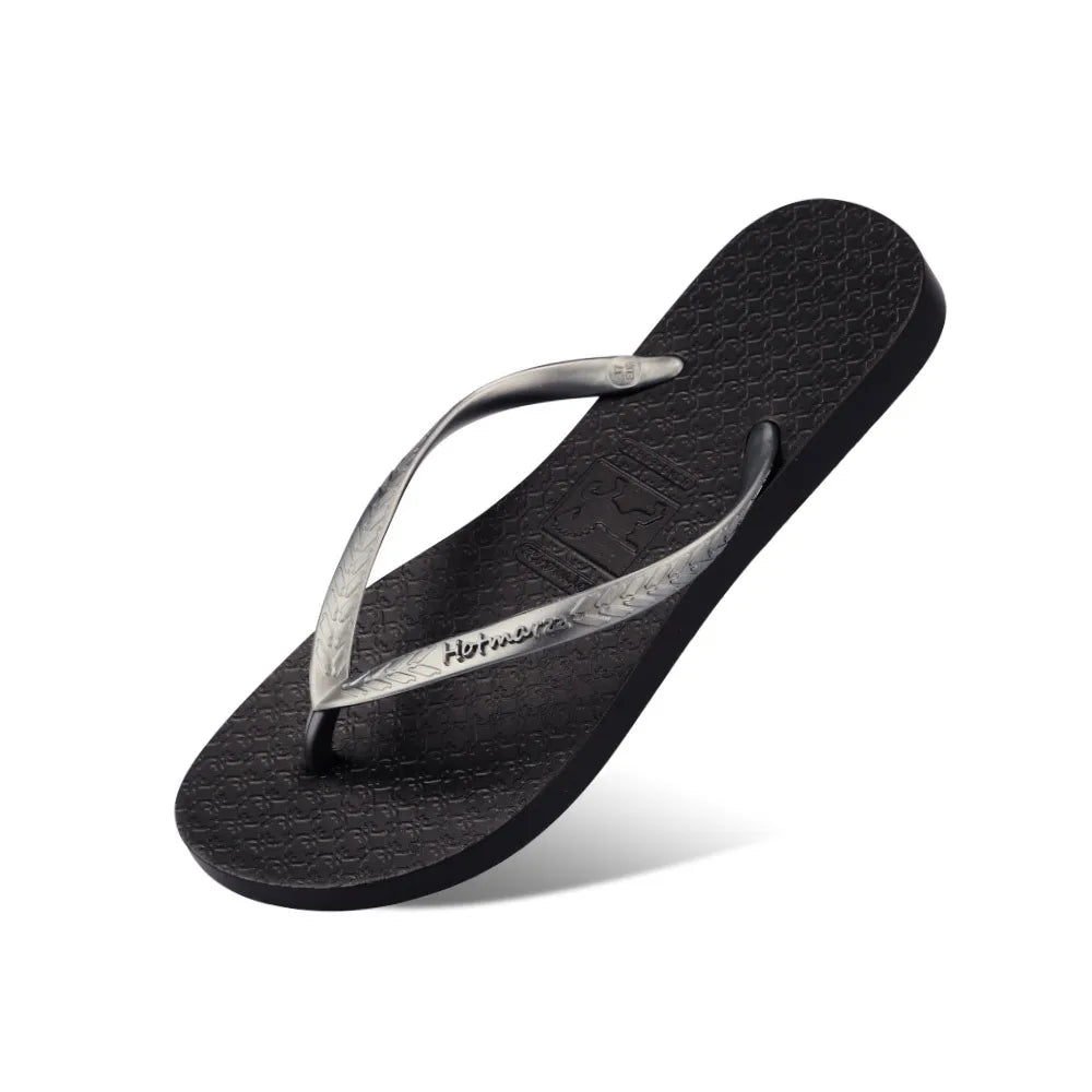 Black toe-post flat sandal, side view of textured sole and thong strap