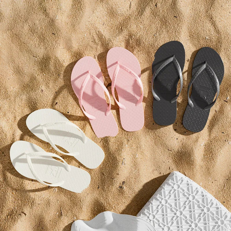Pink, white, and black toe-post flat sandals set with textured straps