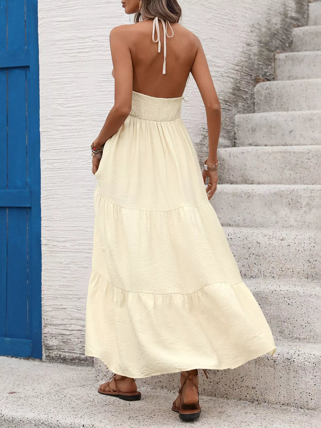 Back of light yellow halter tiered maxi dress with tie straps and layered skirt