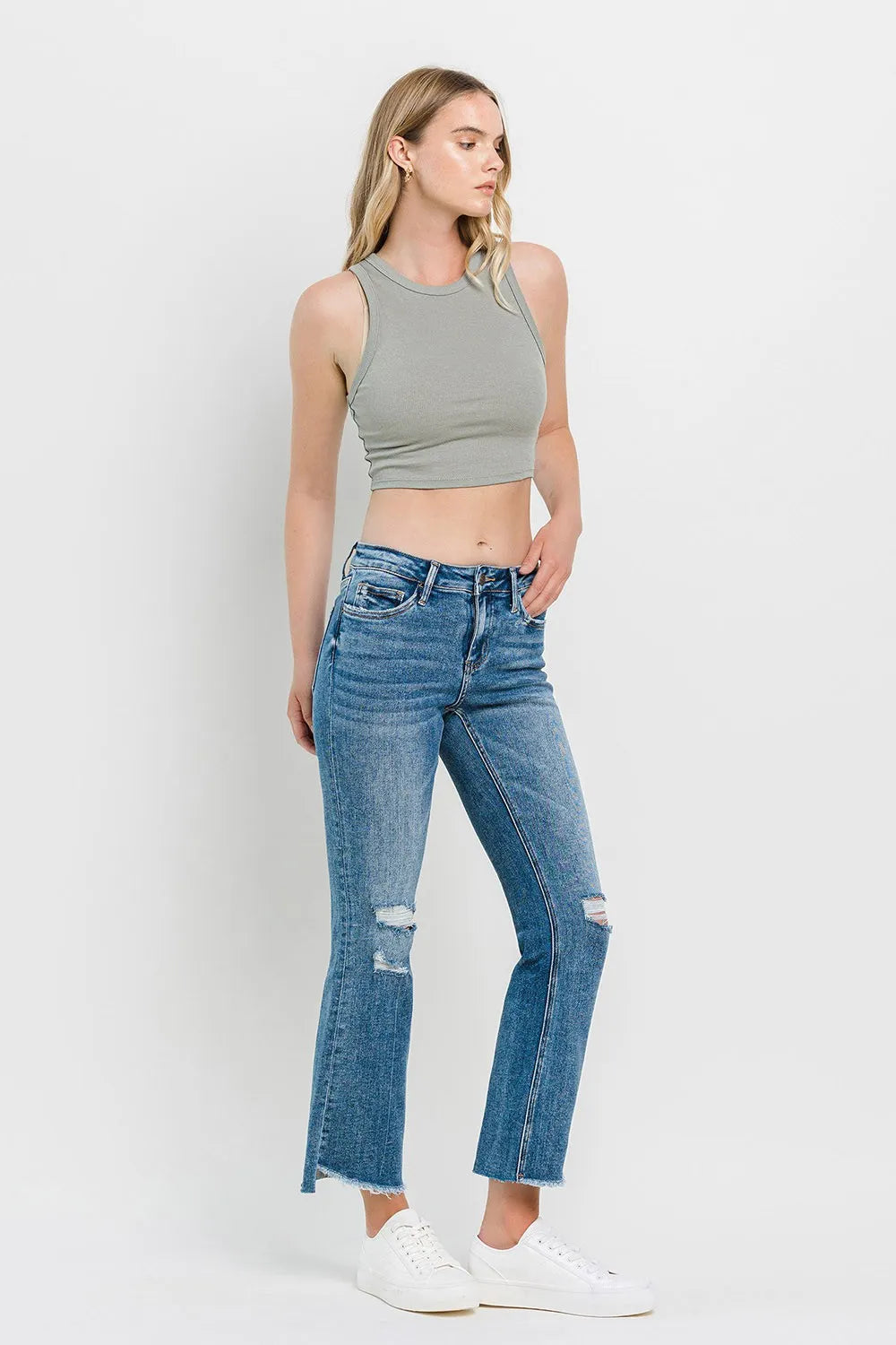 Medium-blue mid-rise flare jeans with side thigh distress, ripped knees, and raw hem