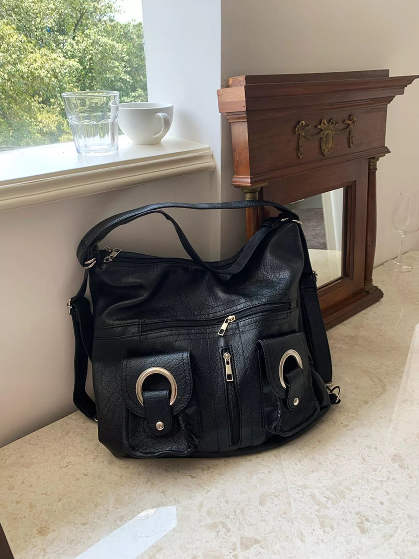 Convertible pocket handbag, black; tabletop view with front buckle pockets and zip top