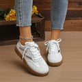 White lace-up sneakers, white laces and tan ribbed sole