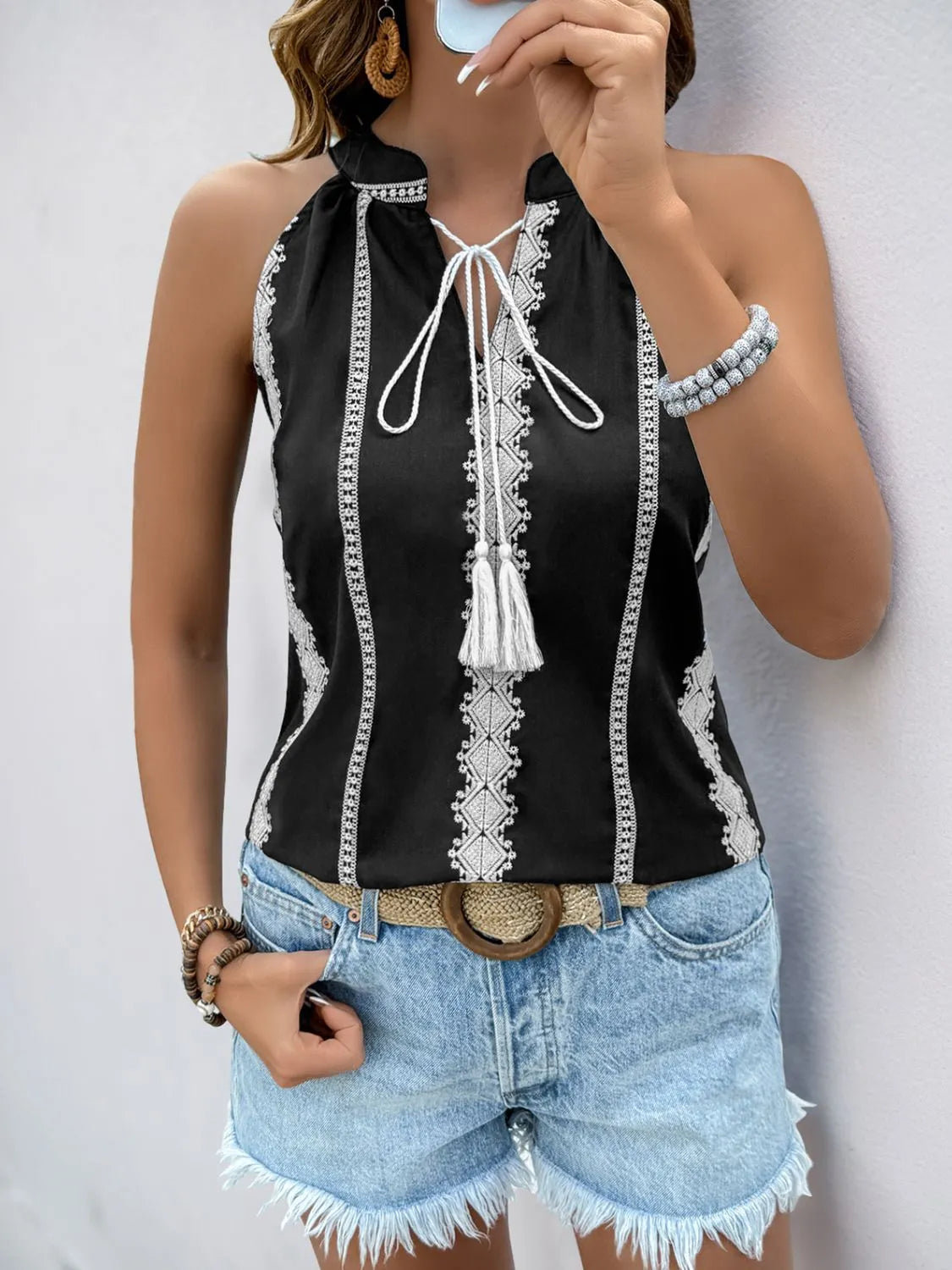 Black halter tank with white embroidered trim, tie neckline, and dangling tassels