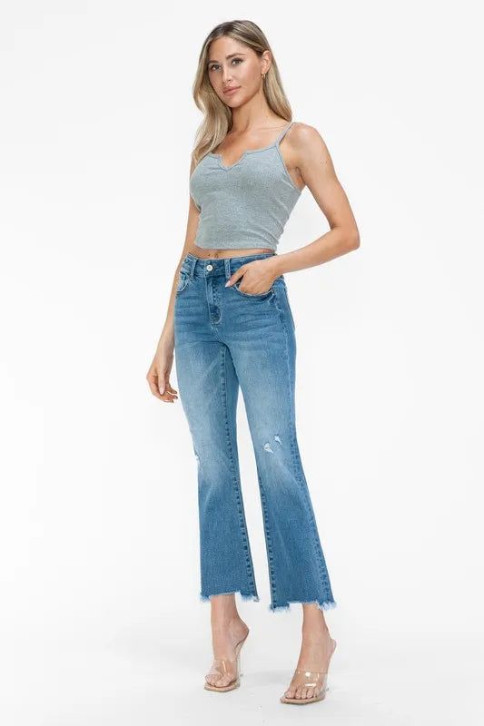Medium-wash mid-rise flare jeans with raw frayed hem and small distressed patches