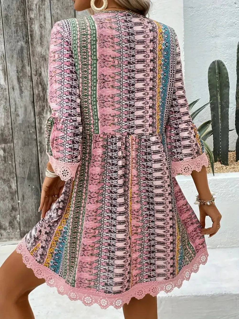 Back view of blush pink striped dress with V-neck, lace hem, and corset panel