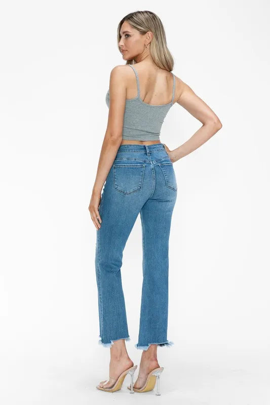 Side view of medium-wash mid-rise jeans with raw frayed hem and faded distressing
