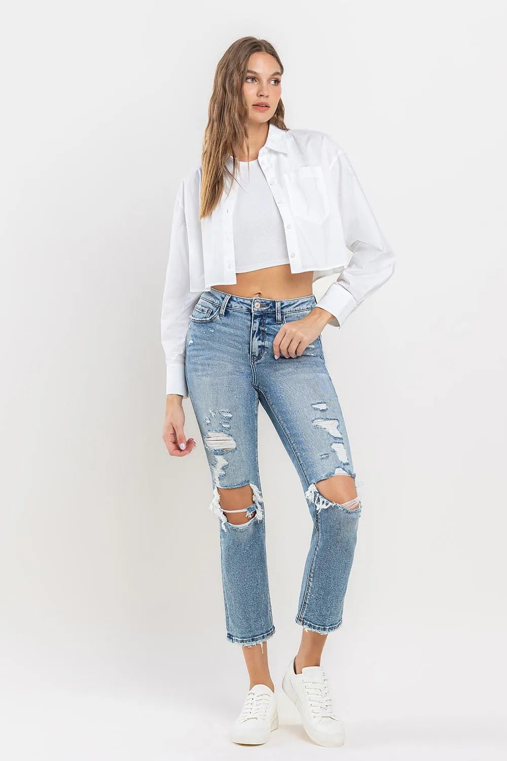 Medium wash high-rise slim straight jeans with large knee rips and distressed thigh areas
