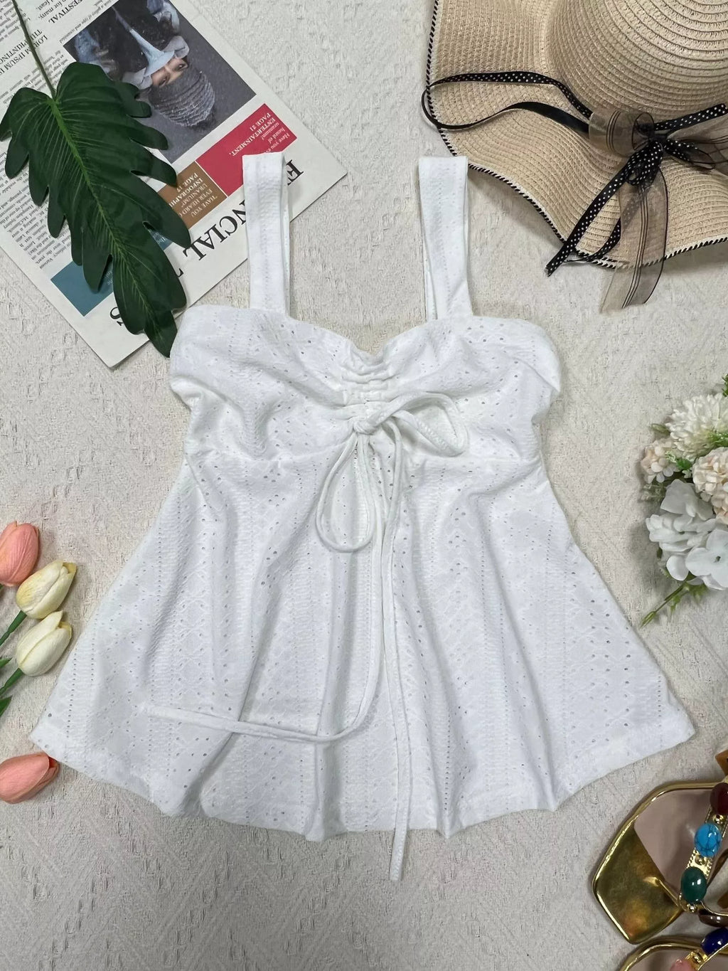 White eyelet cami top with drawstring tie front and gathered, flared hem