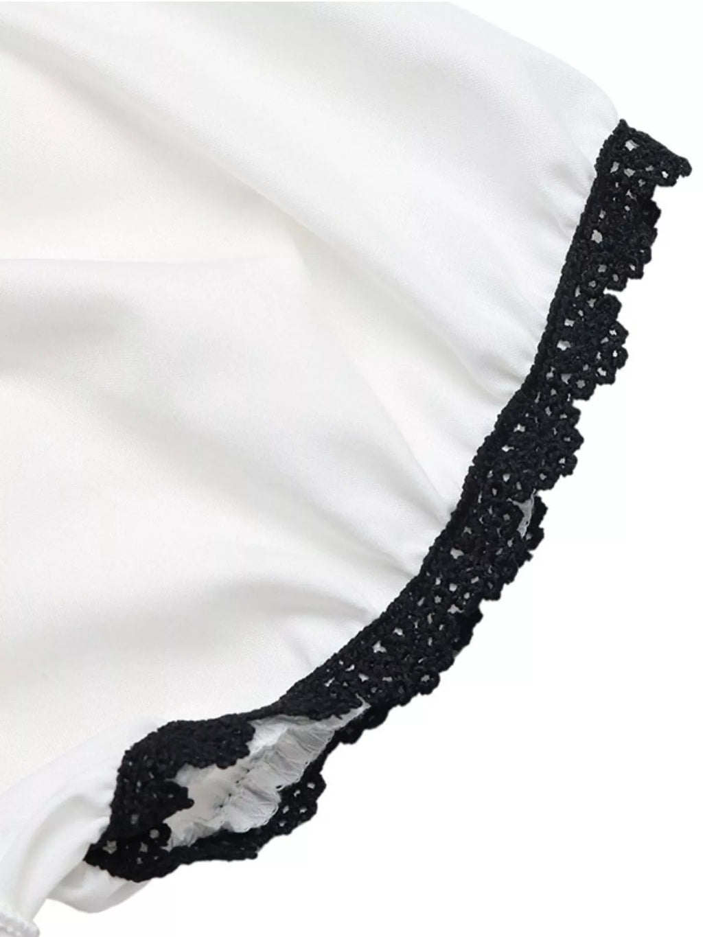 Black lace trim along the edge of a white blouse sleeve