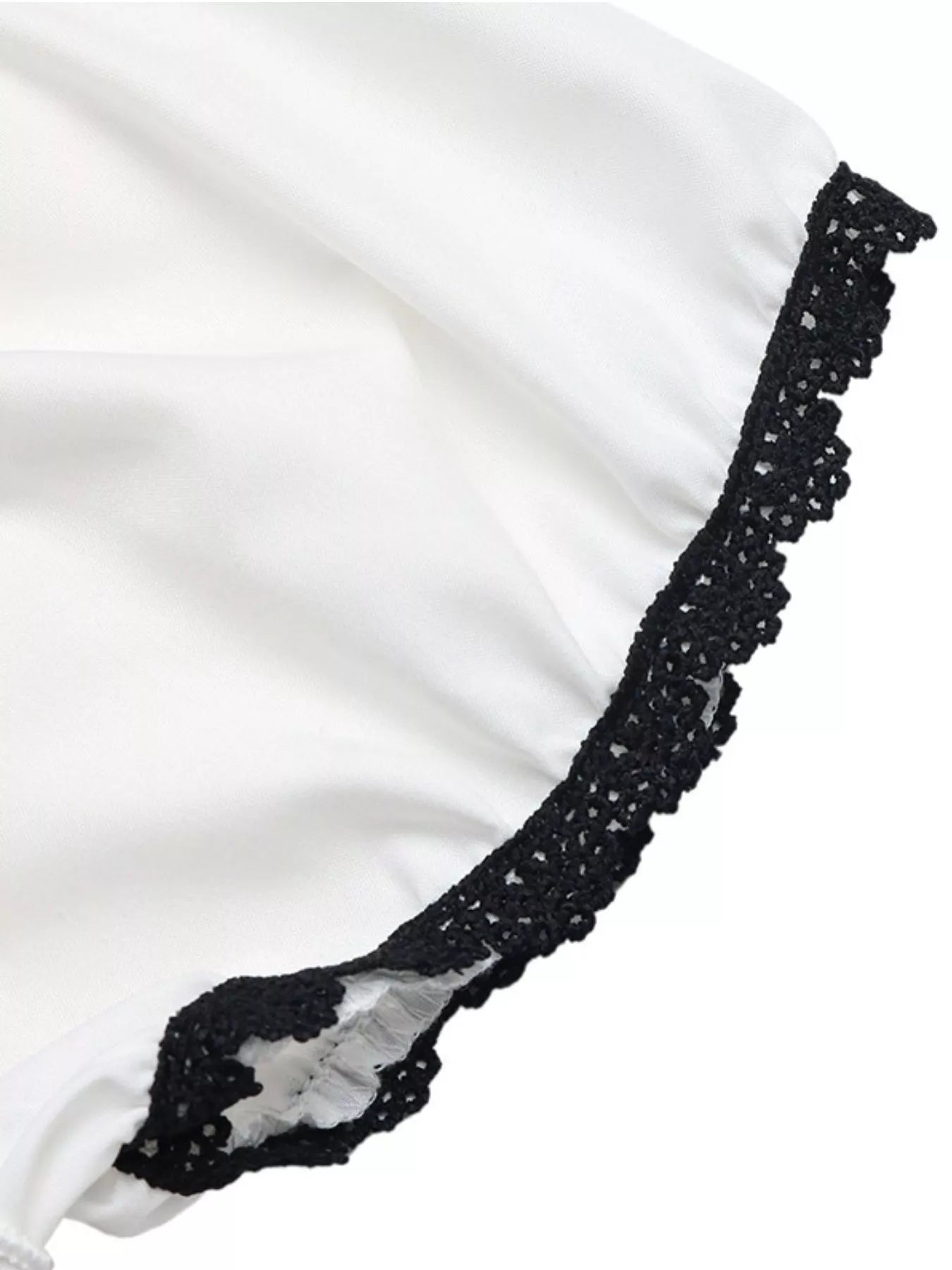 Black lace trim along the edge of a white blouse sleeve