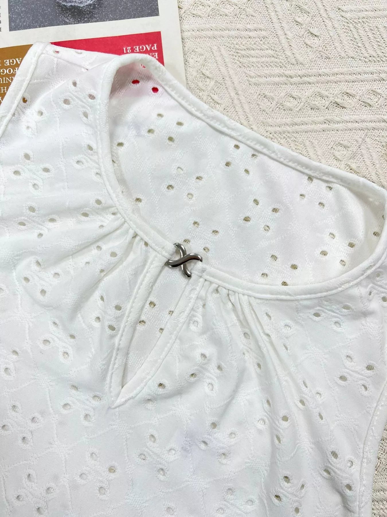 White eyelet cami close-up: round neckline keyhole with loop detail, sleeveless