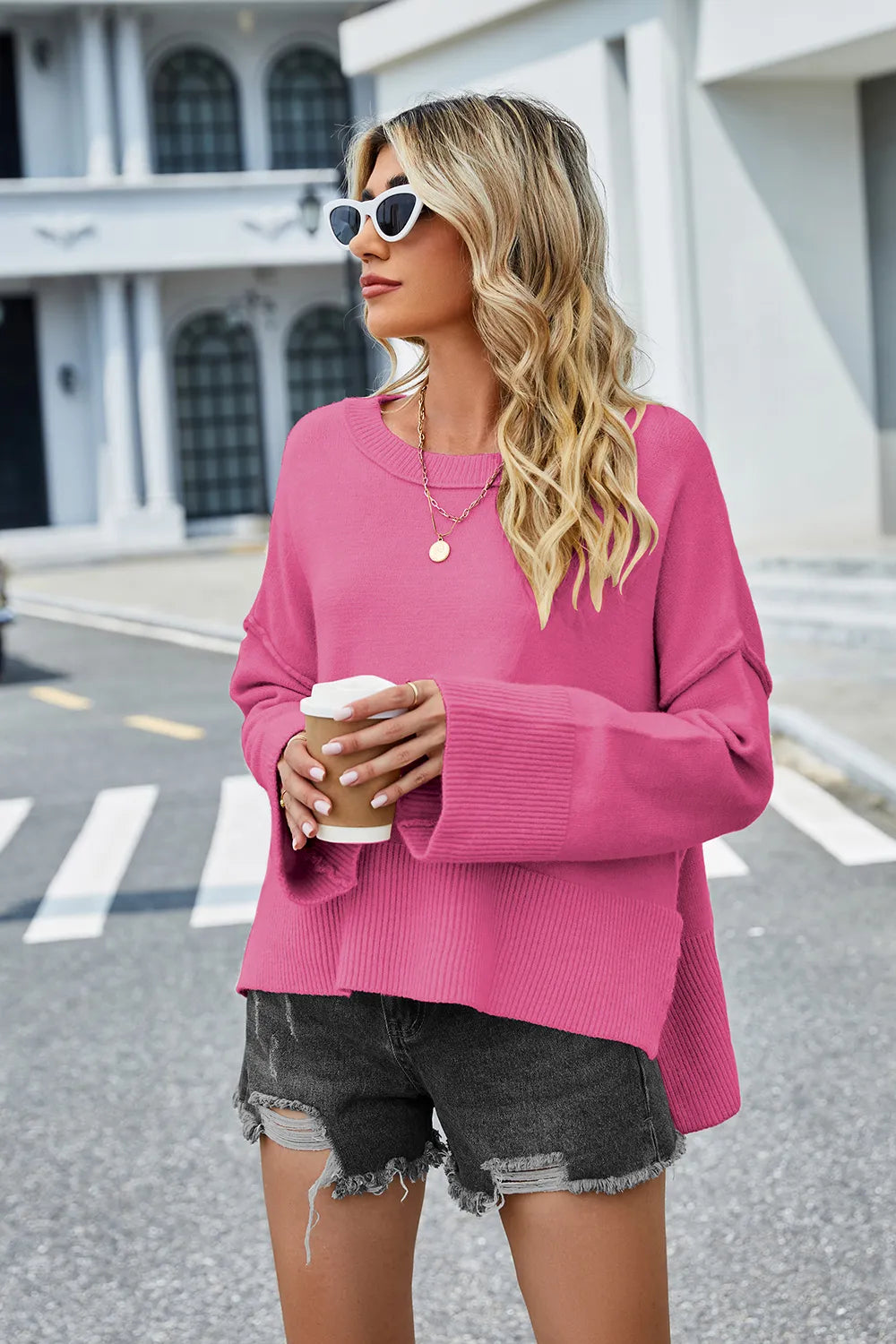 Hot pink round-neck knit sweater with long sleeves and high-low hem slit.
