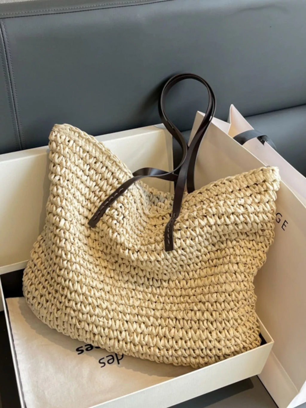 Woven straw shoulder bag with black draw-cord ties and long strap, open tote in tan
