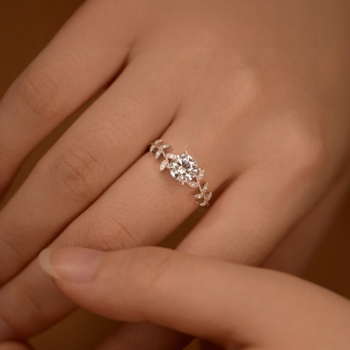 Moissanite leaf ring on hand, round center stone with pavé leaf details