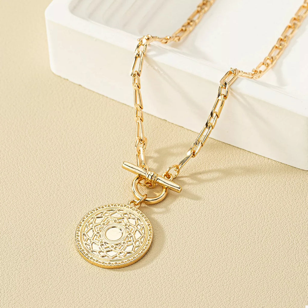 Gold coin pendant necklace with chain links and round textured center design