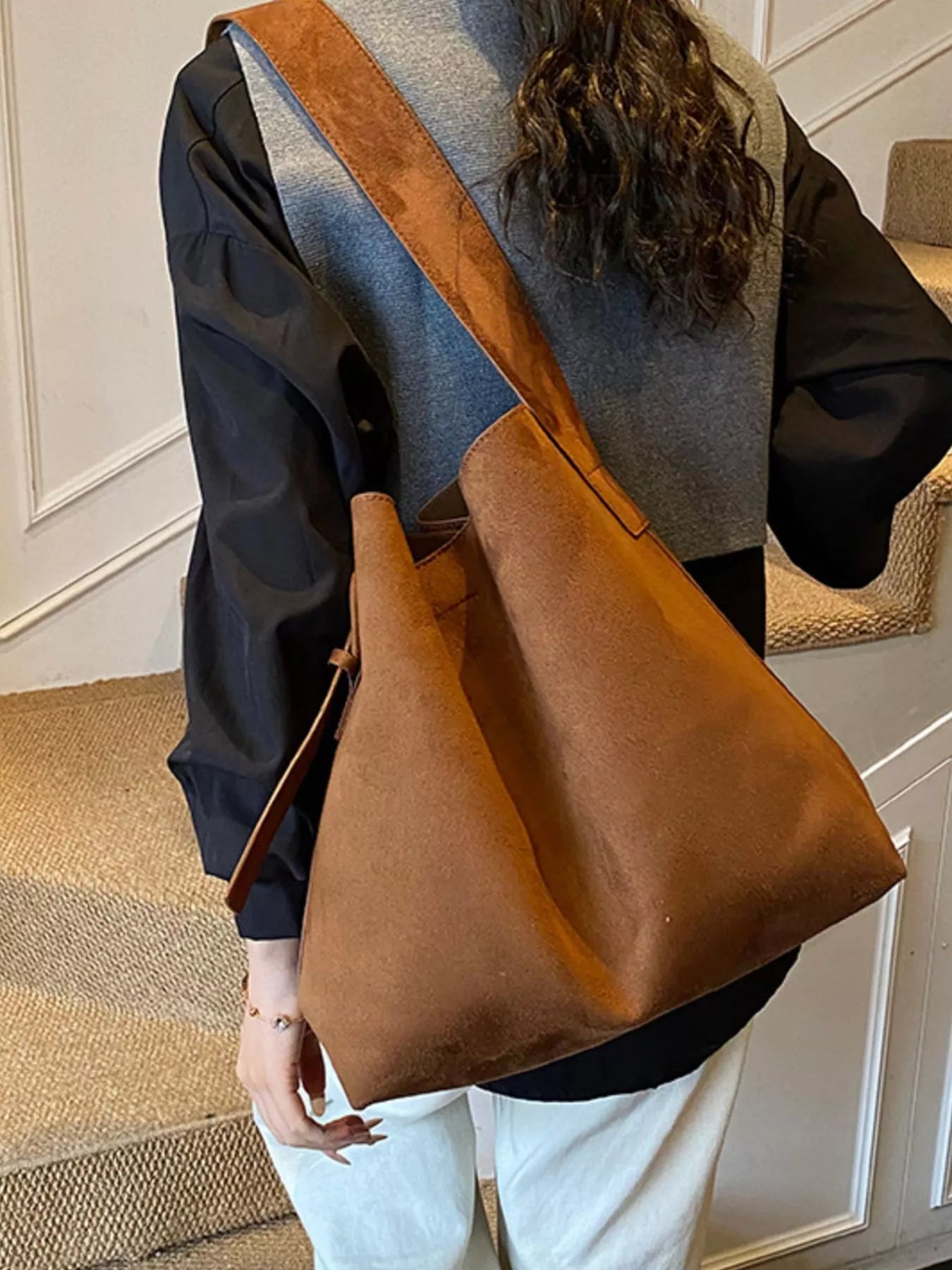 Brown tote bag worn crossbody with adjustable buckle strap