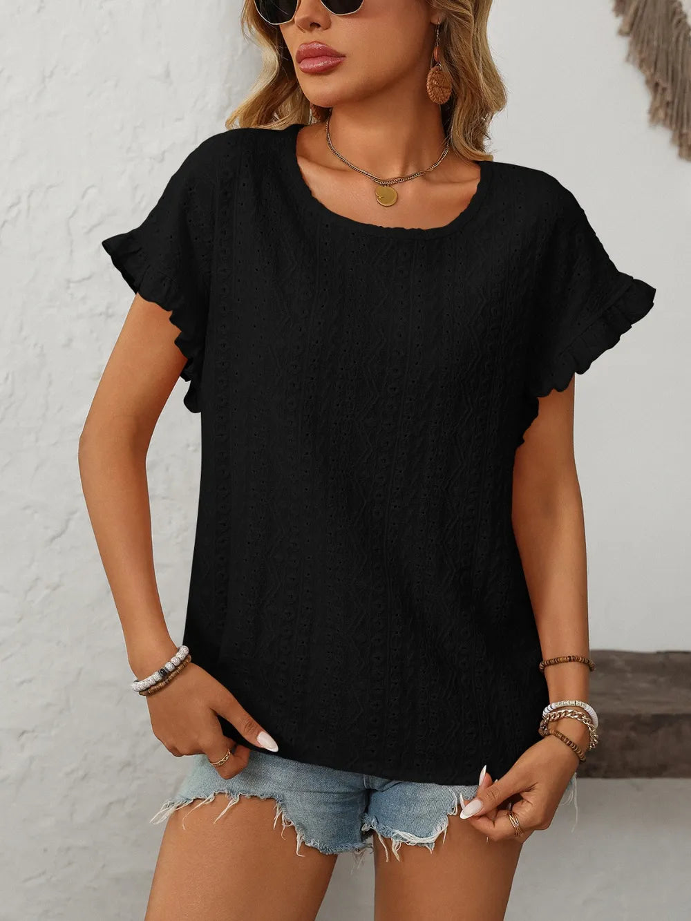 Black eyelet round-neck short sleeve top with flutter sleeves and textured eyelet pattern.