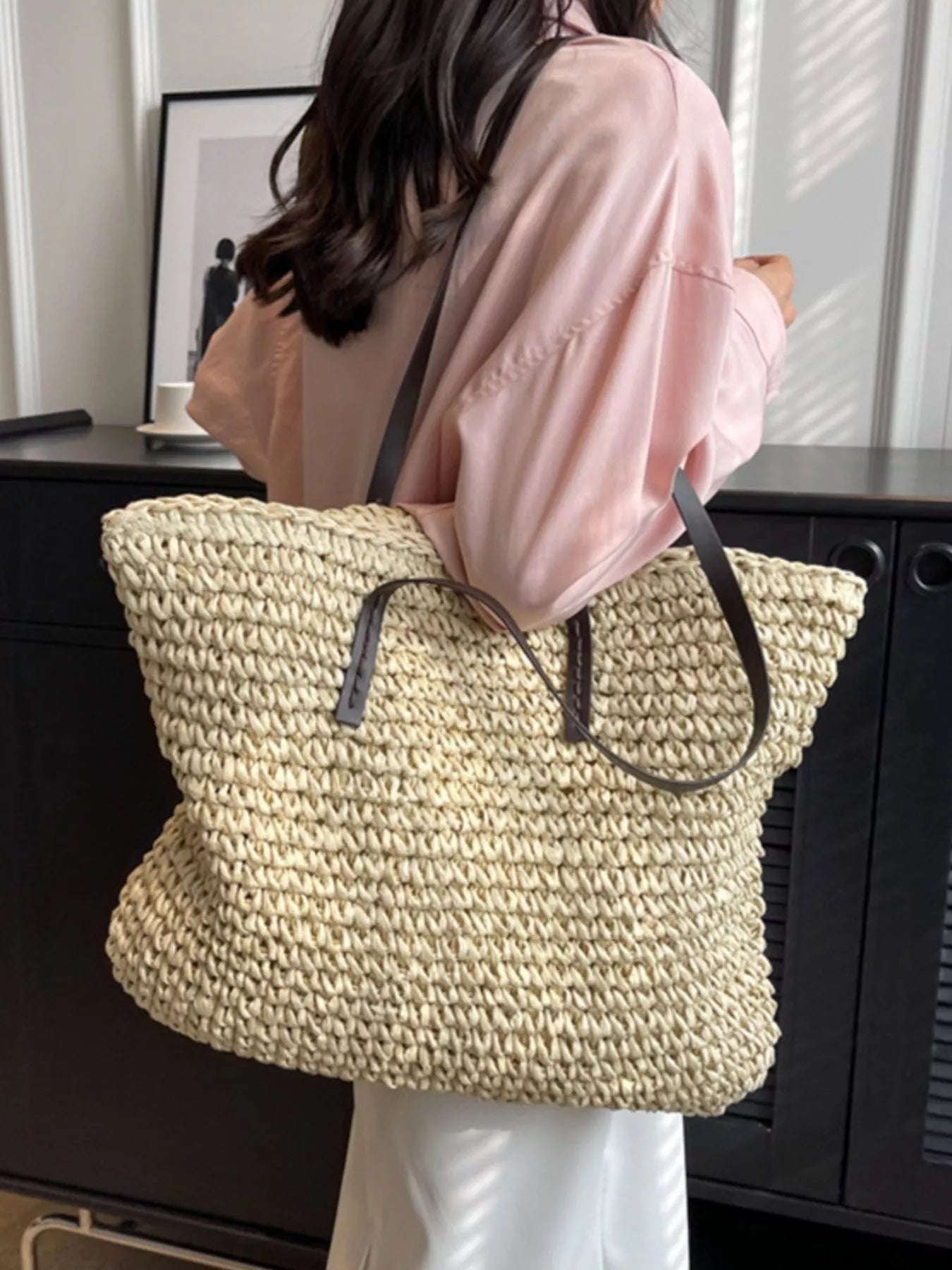 Woven straw shoulder bag with black straps, large open tote in light tan, front view