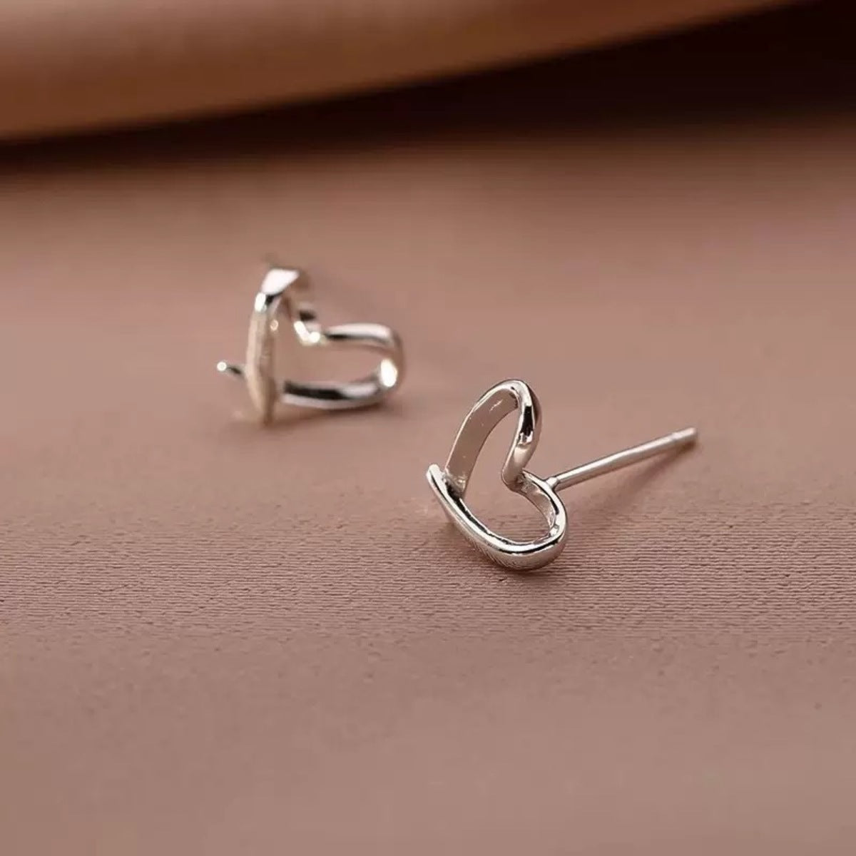 Silver heart-shaped stud earrings, angled view with visible posts
