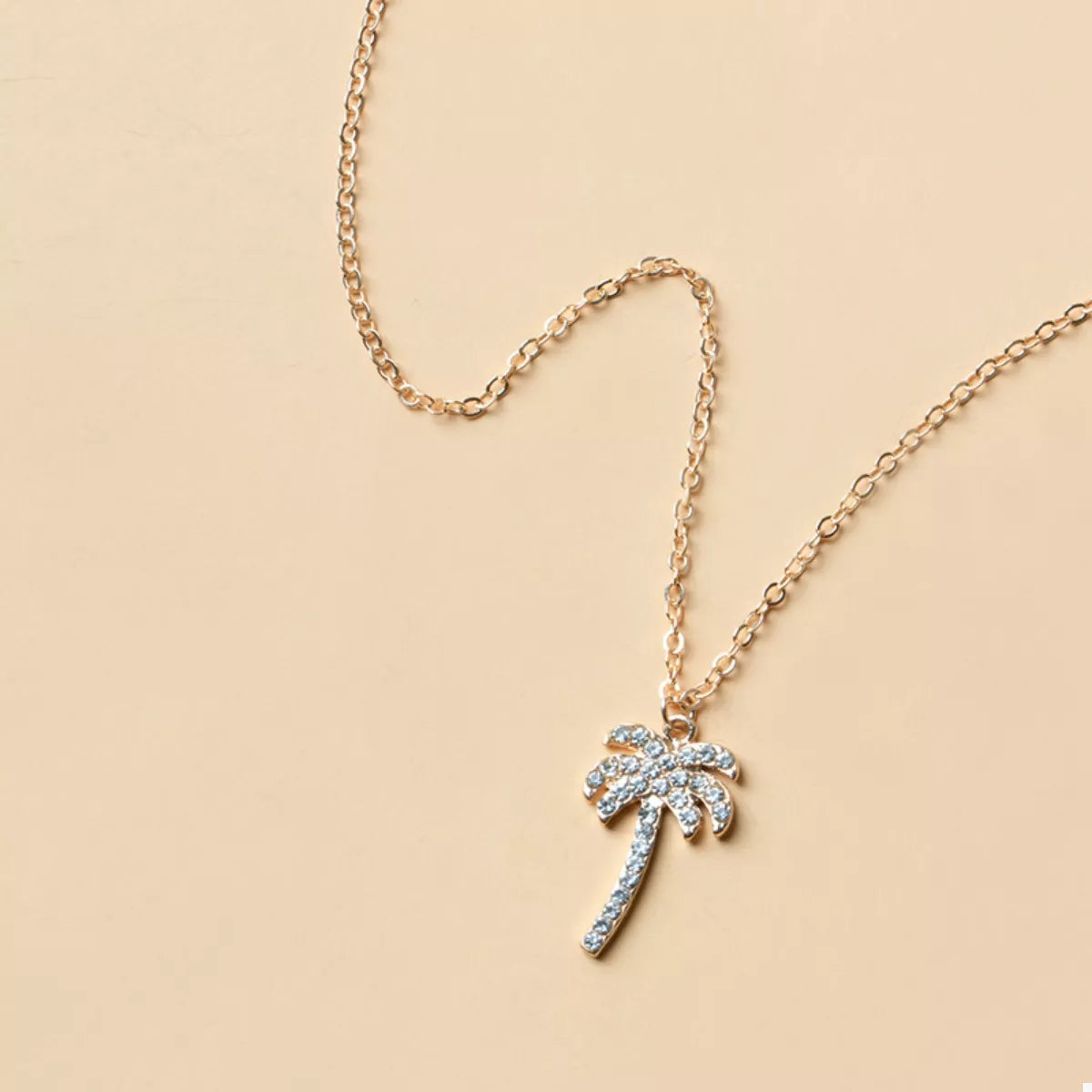 Silver palm tree pendant with blue gemstone accents on a fine link chain