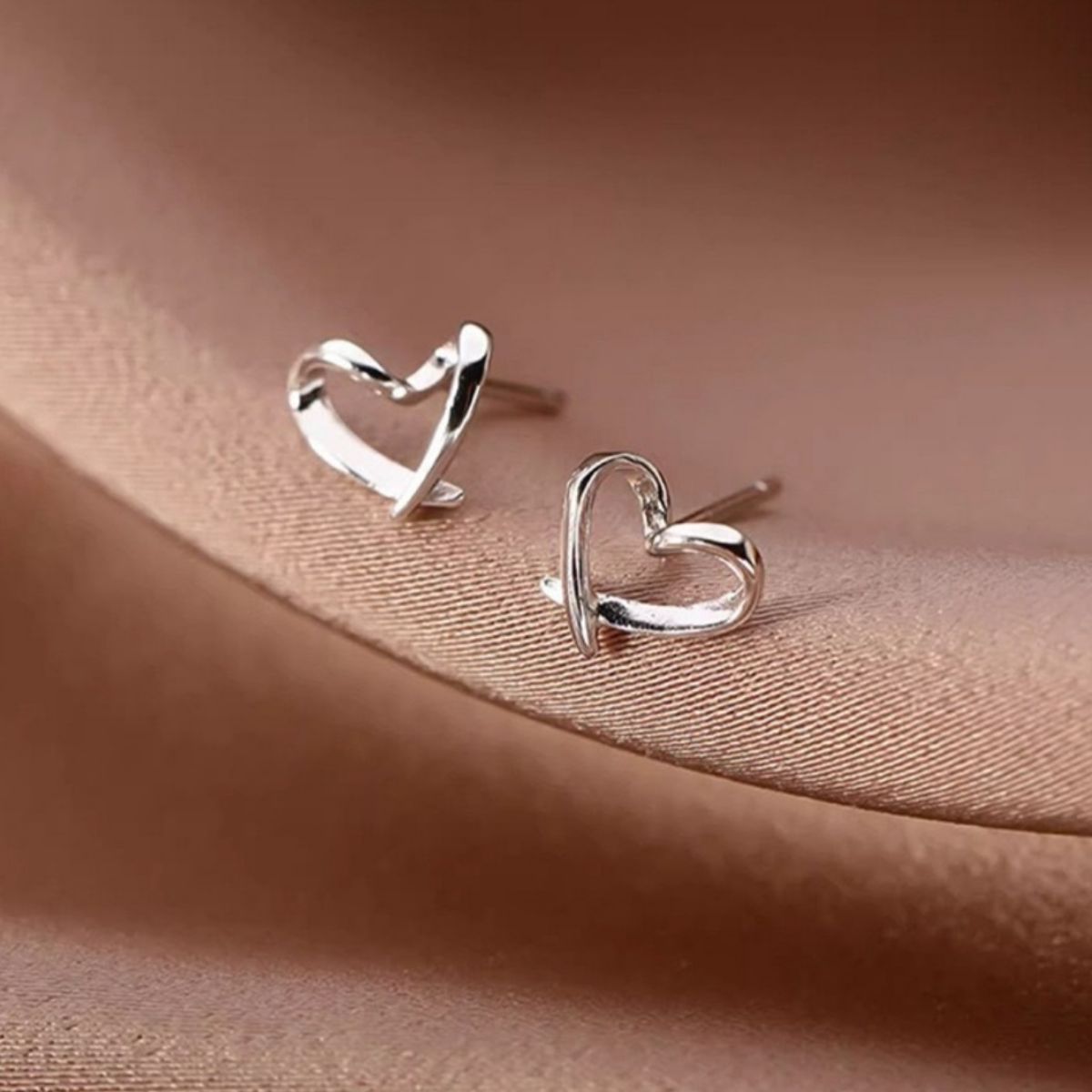 Silver heart stud earrings, close-up showing heart cutout and shine