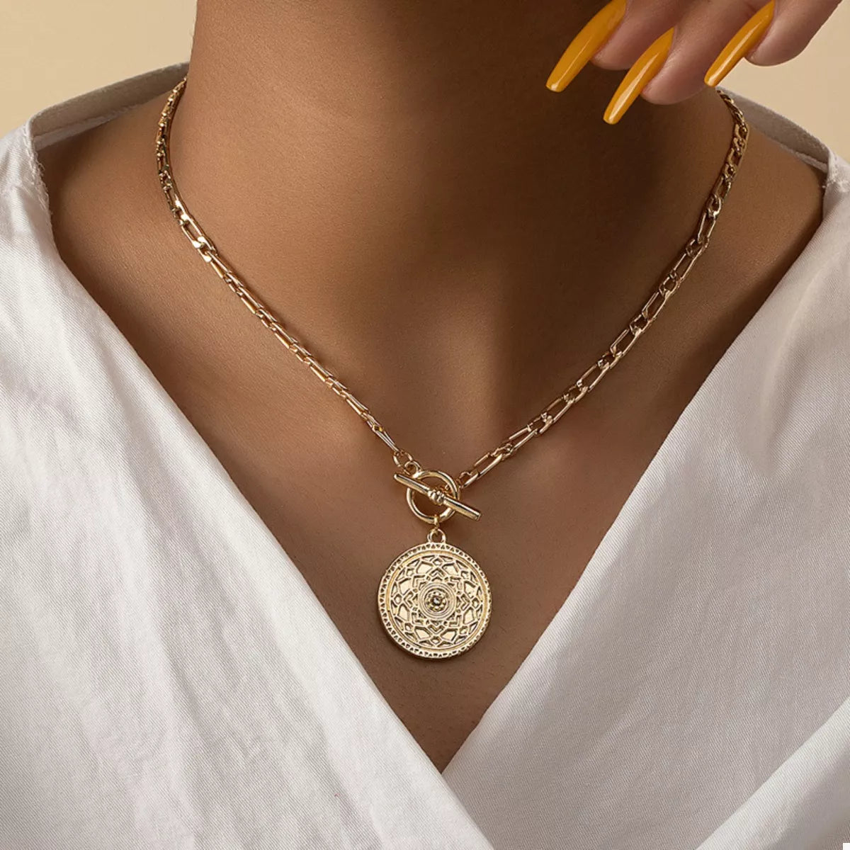 Gold chain link necklace with vintage coin pendant and bow clasp at center
