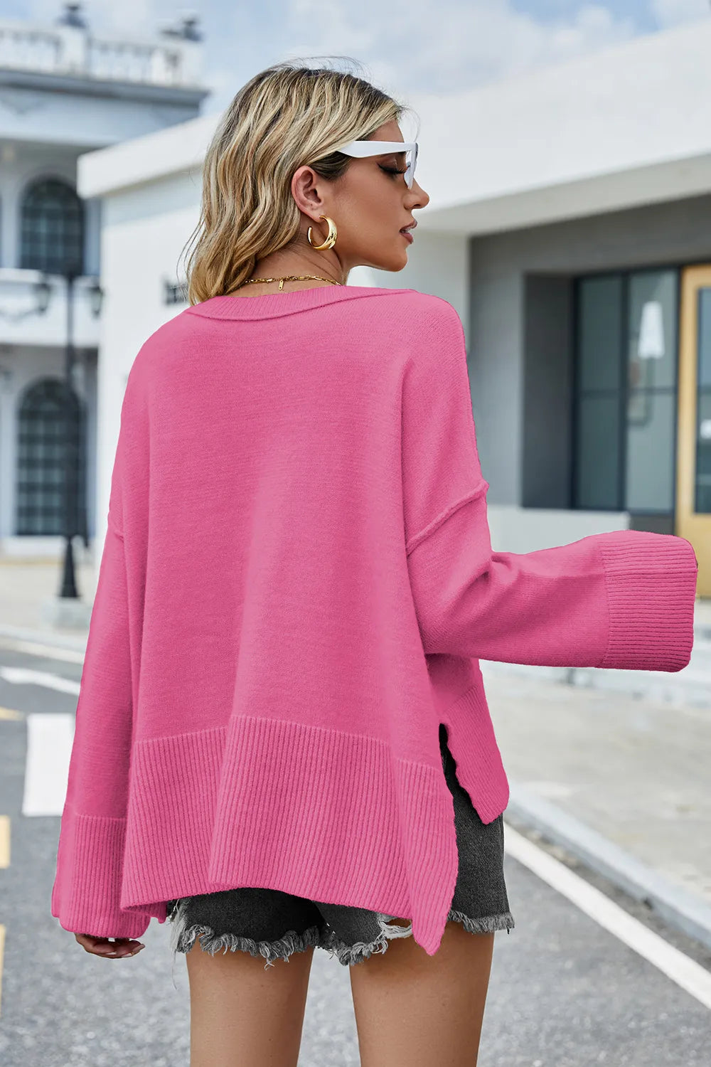 Back view of hot pink high-low slit sweater with ribbed cuffs and hem.