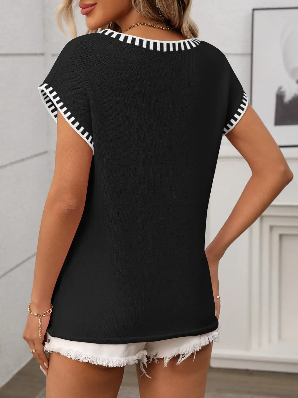 Black v-neck short sleeve knit top with white contrast trim, back view