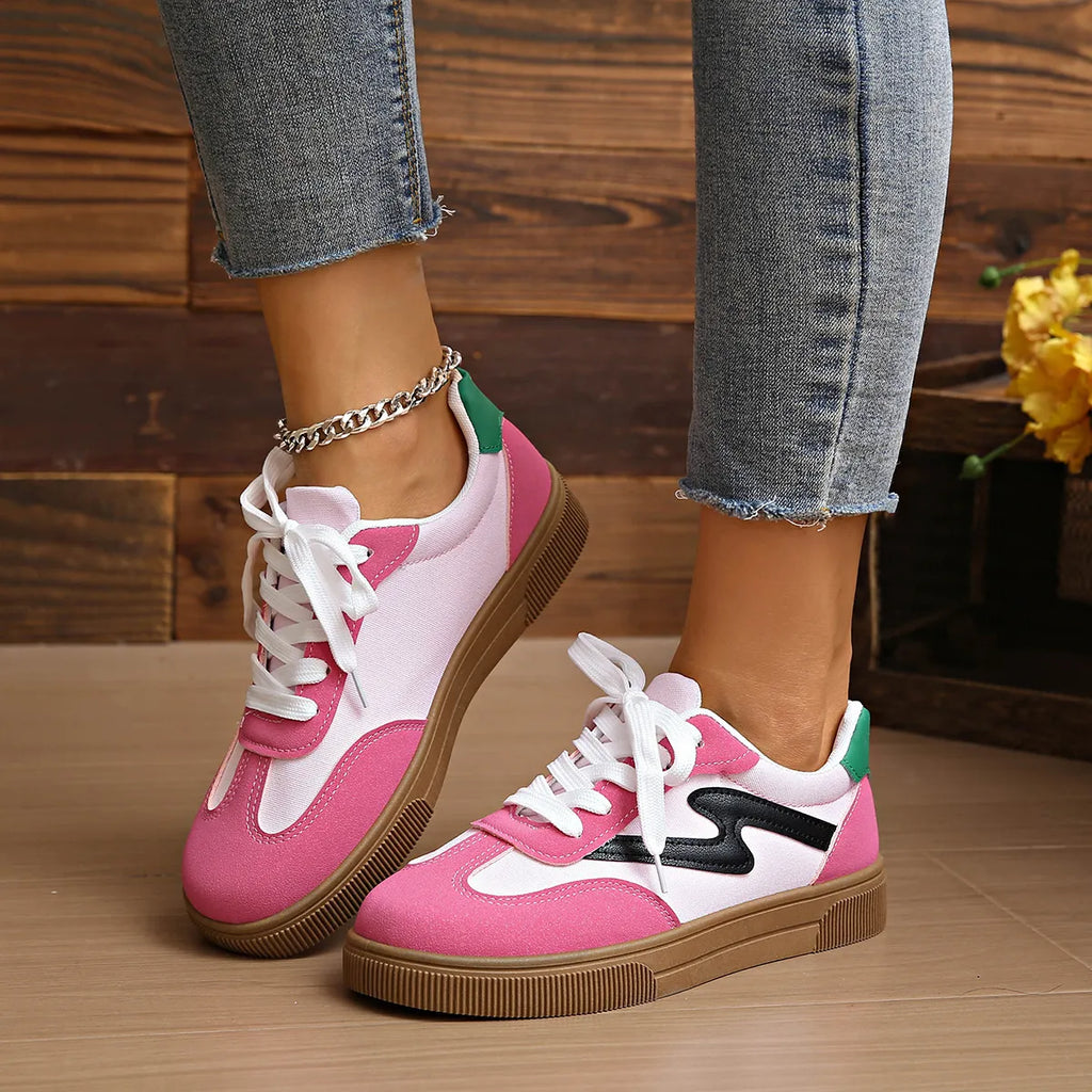 Pink lace-up sneakers with white laces, green heel accents, and tan sole