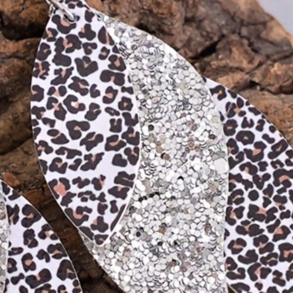 Close-up of silver leopard print and silver glitter leaf drop earrings