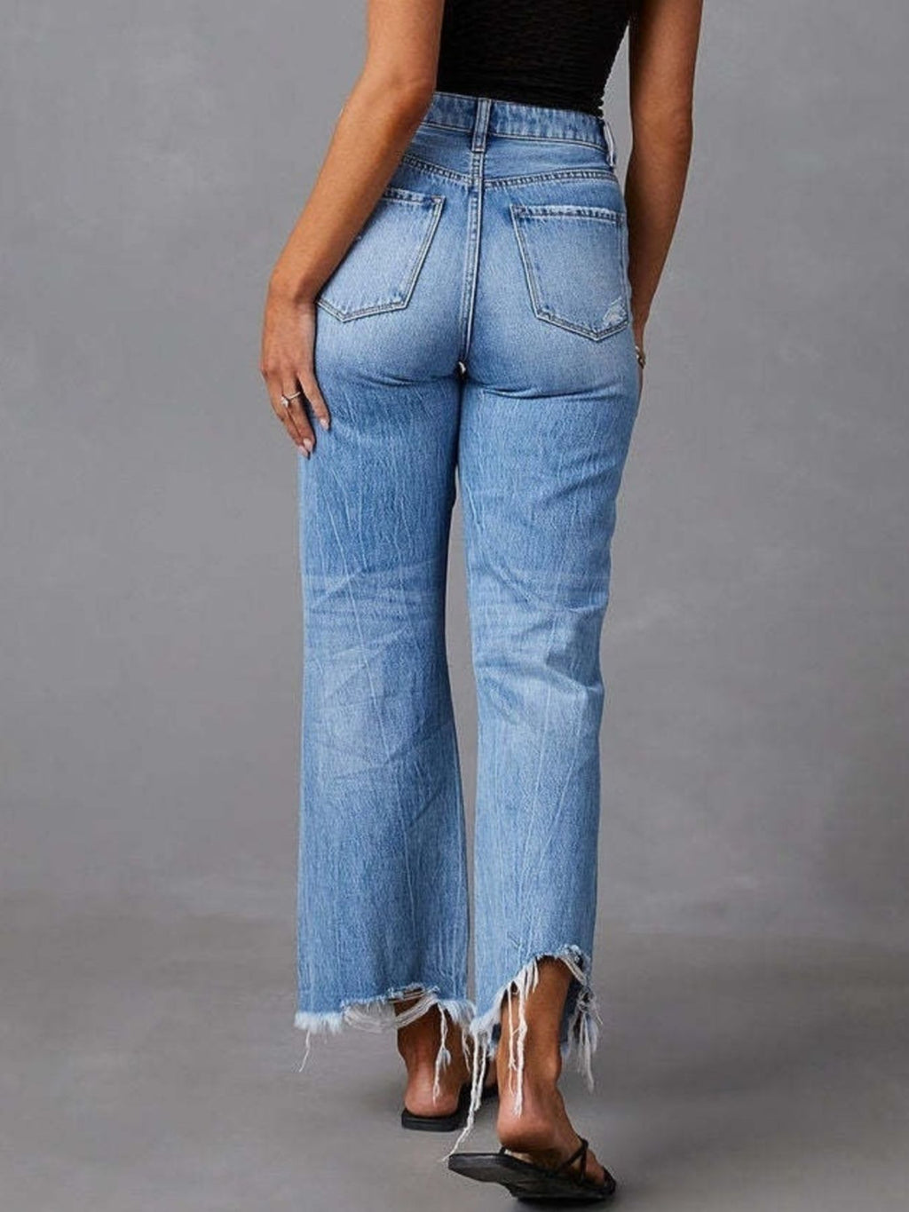 Light blue flare jeans back view with raw frayed hem and distressed leg rips