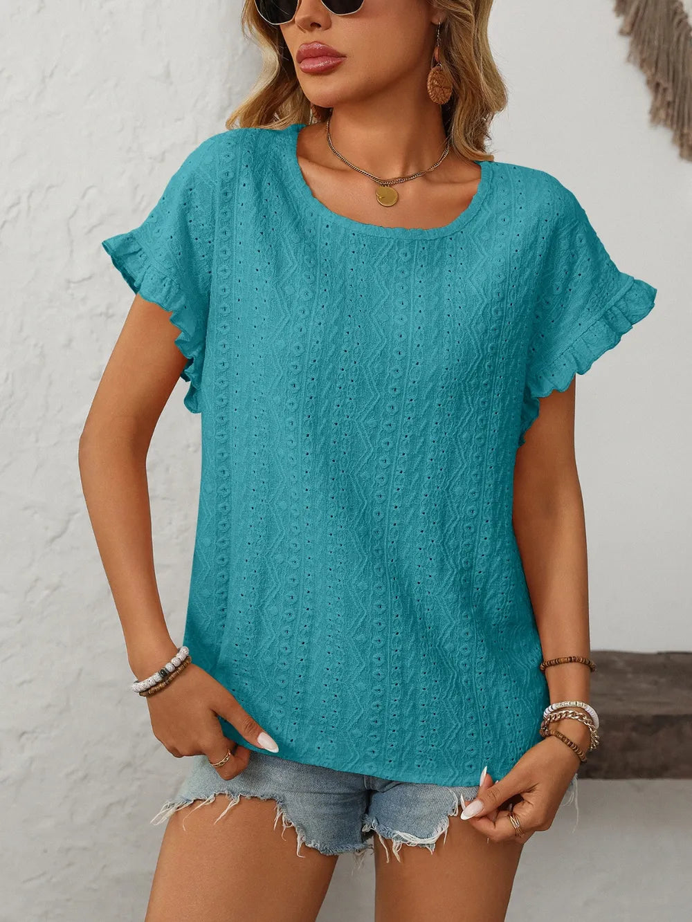 Turquoise eyelet round-neck short-sleeve top with flutter sleeves and vertical textured design.