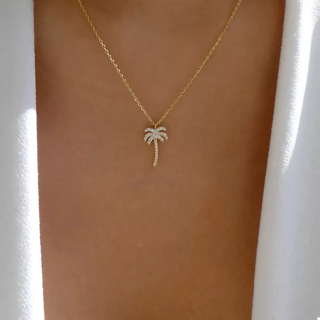Gold palm tree pendant necklace with small sparkle details on a fine chain