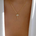 Gold palm tree pendant necklace with small sparkle details on a fine chain