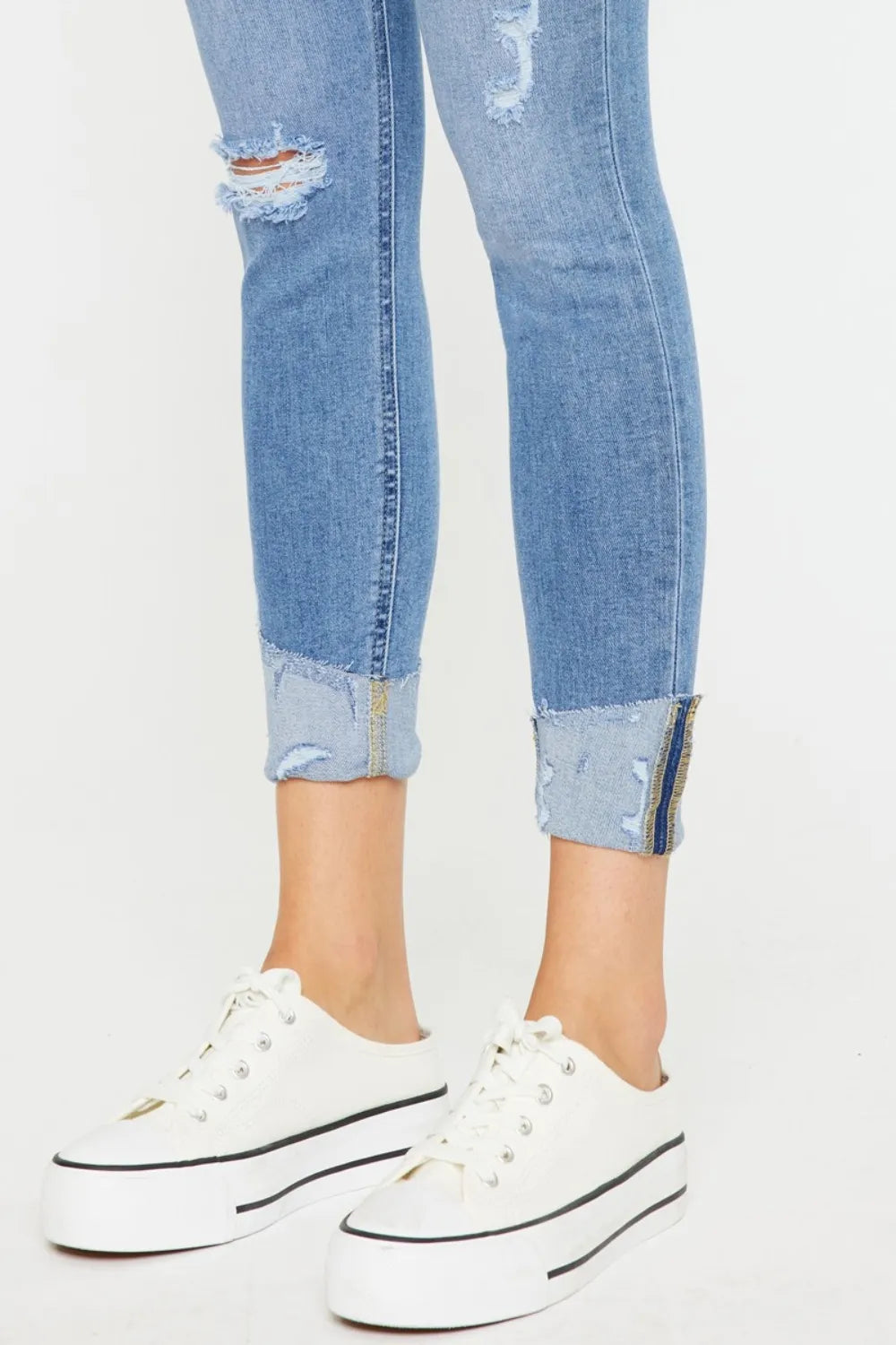 Cuffed light wash button-fly jeans with ankle rips and frayed patch at hems