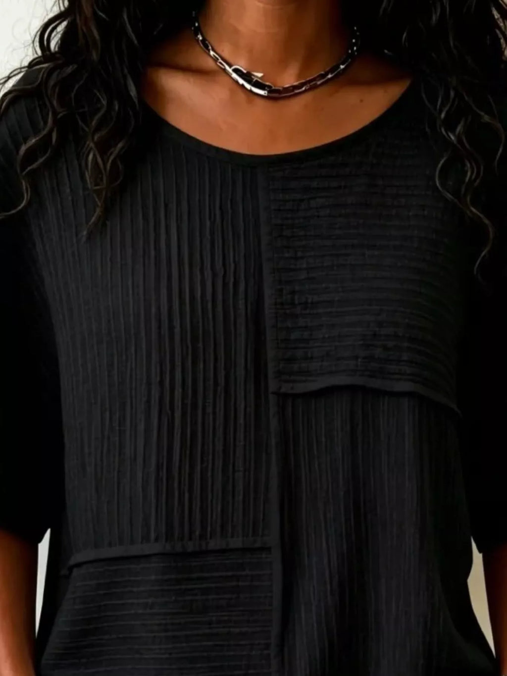 Textured black round-neck half-sleeve blouse with vertical rib pattern and front pocket panel
