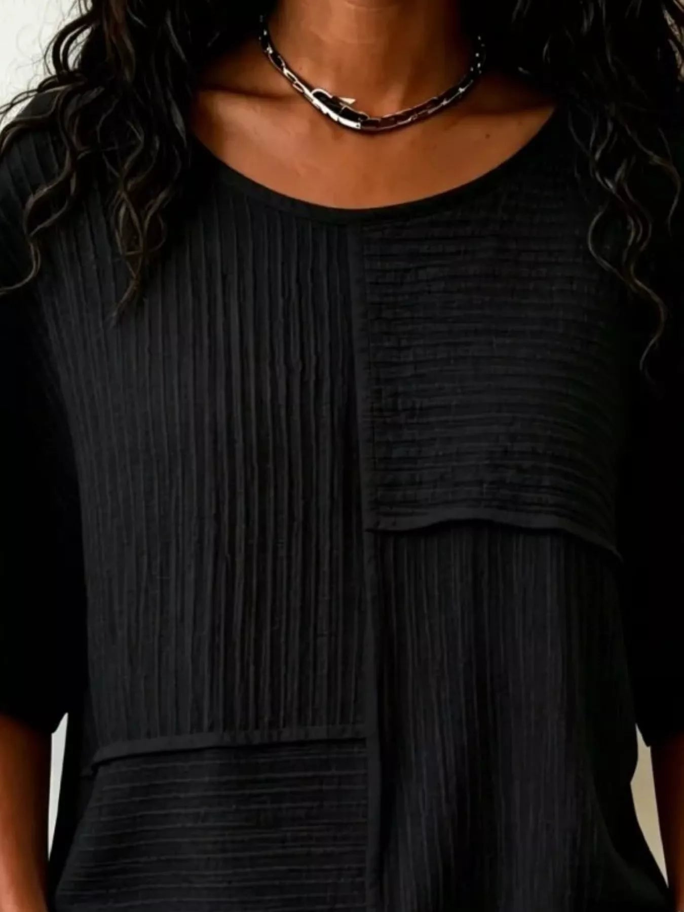 Textured black round-neck half-sleeve blouse with vertical rib pattern and front pocket panel