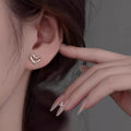 Silver heart-shaped stud earrings on ear, heart face design