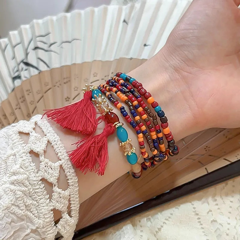 Multicolor bead tassel bracelet with red tassels and gold-tone charm details