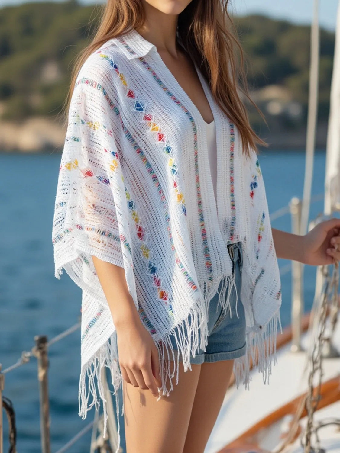 White openwork knit cape with colorful dot pattern, long fringe and wide draped sleeves
