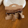 Coffee brown and dark bead tassel bracelet with gold-tone charms and hanging tassel