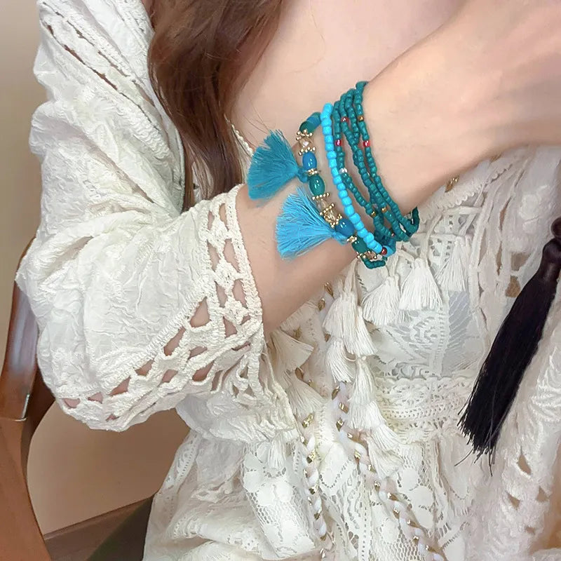 Turquoise bead tassel bracelet with blue tassels and gold-tone charm details