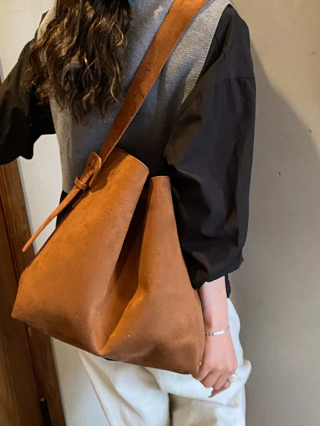 Tan-brown tote bag with adjustable strap, side tie detail, and slouchy body