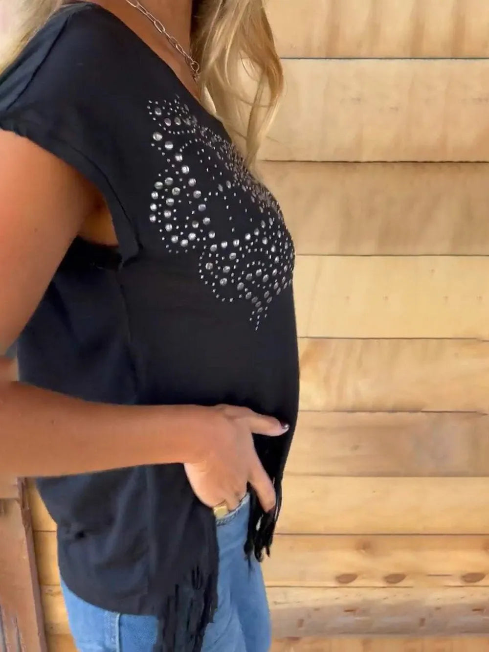 Black short-sleeve tee with round neck, studded heart pattern, and side fringe detail