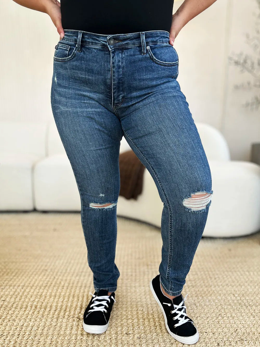 Dark blue slim jeans with ripped knee details and light-wash distress across thighs