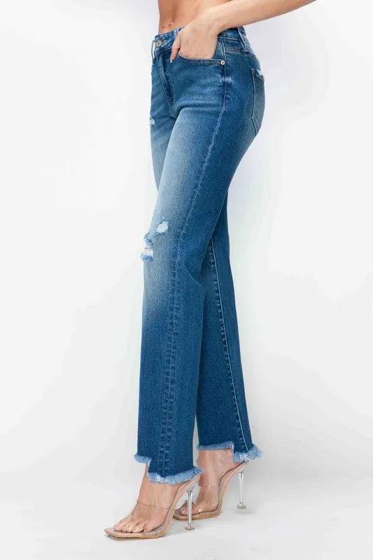 Side view of medium-wash straight jeans with ripped knee detail and raw frayed hem