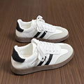 White lace-up sneakers with black side stripes and lace-up front