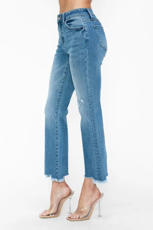 Side close-up of medium-wash mid-rise flare jeans with raw frayed hem and fading